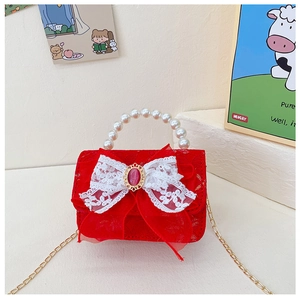 Détail du sac fille en dentelle rouge avec nœud géant, poignée perle et bandoulière