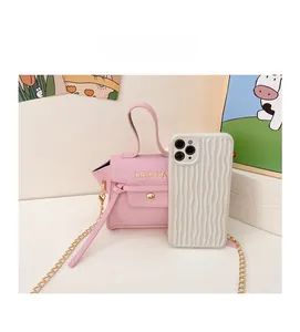 Mini borsa rosa da bambina in pelle martellata accanto a un telefono per le dimensioni