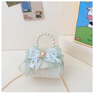 Détail du sac à main enfant en dentelle verte avec anse perle, nœud tulle et chaîne