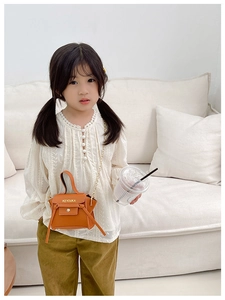 Dettaglio di una mini borsa arancione per bambina con catena d'oro e manico