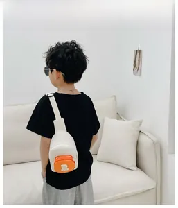 Vue détaillée d'un enfant portant un sac bandoulière blanc avec poche orange et logo ours