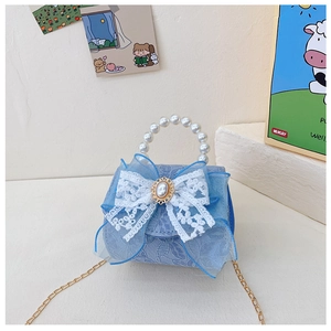Détail du mini sac en dentelle bleue avec nœud en maille, poignée perle et chaîne