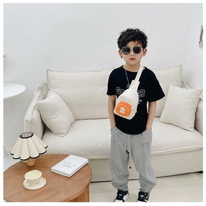 Sac de poitrine pour enfant beige et orange avec patch lettre R porté par un garçon