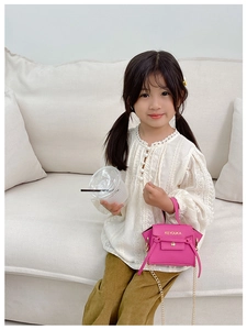 Dettaglio di una mini borsa a tracolla rosa per bambina con catena d'oro e texture