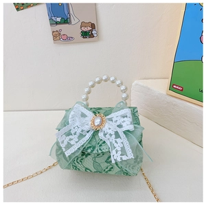 Détail d'un sac en dentelle vert clair avec un nœud blanc et une anse en perles