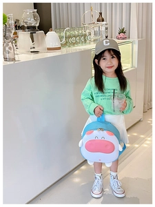 Sac à dos enfant motif animal mignon porté par un modèle dans un café lumineux