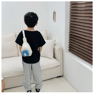 Vue de dos d'un enfant portant le sac bandoulière en toile crème avec poche bleue