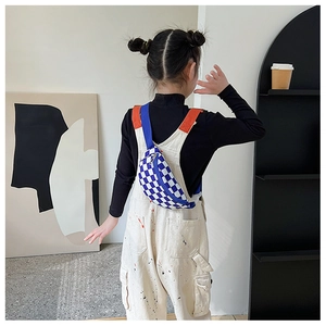 Sac de poitrine enfant à motif damier bleu et blanc porté par un jeune mannequin