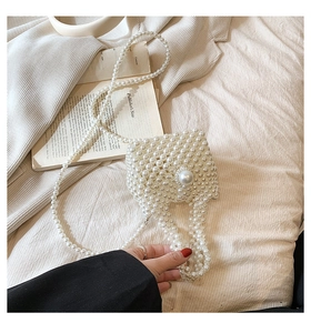 Detailed macro view of white pearl beaded mini flap bag with a large pearl clasp and chain