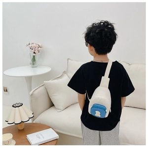 Sacoche enfant avec poche bleue zippée et écusson ours porté par un enfant à la maison