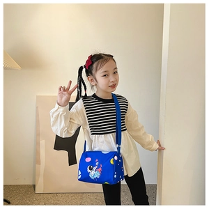 Close-up of blue cylinder kid bag with astronaut print and adjustable strap for girls
