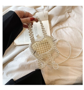 Detailed view of girl's white pearl woven handbag with top handle and crossbody chain