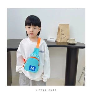 Junge im Streetwear-Stil trägt eine hellblaue Crossbody-Brusttasche mit orangefarbenem Gurt