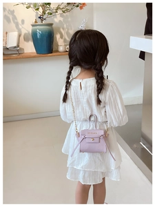 Mini borsa a tracolla color lavanda per bambina con catena dorata in un interno moderno