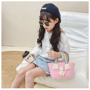 Close-up of pink woven kids' handbag with cute plush bunny and rainbow strap detail