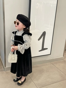 Detail of girls' black velvet dress paired with a stylish pearl handbag and beret