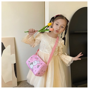 Detailed view of pink canvas crossbody bag with cute bunny and strawberry prints on girl