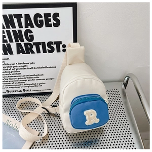 Détail du sac de poitrine enfant crème et bleu avec écusson lettre R en broderie