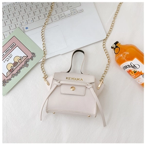 Dettaglio di mini borsa beige con trama a grana e raffinata catena dorata lucida