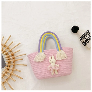 Detail of pink straw basket with rainbow handles and a cute bunny doll accessory