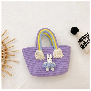 Detail of purple woven kids handbag with rainbow handles and a cute bunny doll charm