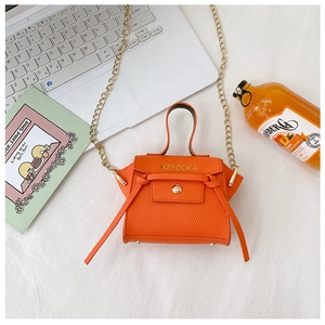 Dettaglio mini borsa arancione in pelle martellata con catena oro e logo del brand