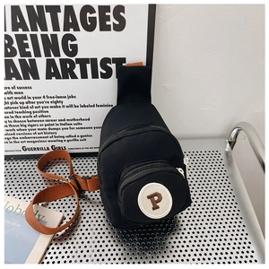 Détail du mini sac bandoulière noir avec écusson P sur plaque métallique argentée