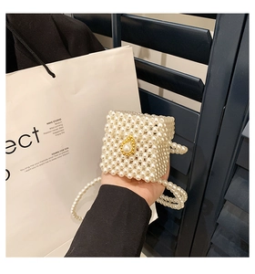 Close-up of white imitation pearl woven mini bag with luxury gold buckle detail