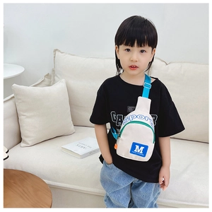 Detail der weißen Kinder-Umhängetasche mit blauem M-Logo und verstellbarem Gurt am Model