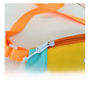 Gros plan sur la fermeture éclair blanche et la sangle orange d'un sac de poitrine pour enfant