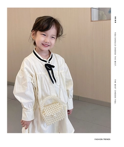 Detail of girls' pearl woven crossbody bag with elegant top handle and bead shoulder strap