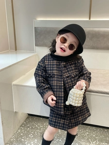 Detail of a young girl holding a white pearl bucket bag with a brown plaid autumn outfit