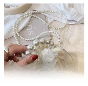 Close-up of handmade mini pearl bucket bag with white ribbon flower and pearl strap