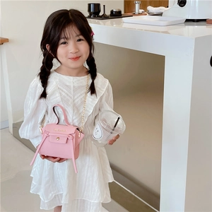 Mini borsa a tracolla rosa da bambina con catena dorata e manico su una modella