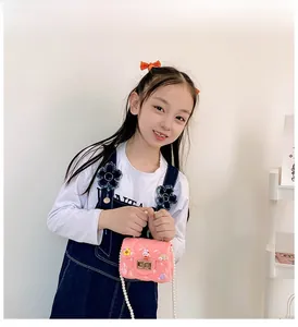 Pink mini jelly bag with pearl strap, floral charms and quilted texture worn by child