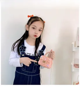 Mini borsa in silicone rosa con trama trapuntata e catena di perle indossata da bimba