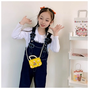 Close-up of kids yellow silicone jelly bag with pearl handle and cartoon charms