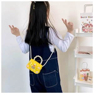 Detail of yellow silicone mini crossbody bag with pearl handle and cute 3D charms