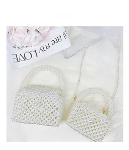 Detail of handmade faux pearl woven handbags for girls on white soft tulle fabric