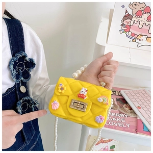 Close-up of yellow silicone girls purse with pearl handle and cute cartoon charms