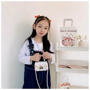Detail of white quilted silicone mini bag with pearl handle and cartoon charms