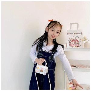 Close-up of children's white quilted bag with colorful floral charms and pearl handles
