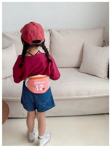Vue arrière d'un enfant portant un sac banane en toile rose avec texte dans un décor de maison