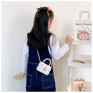 Child wearing a white quilted crossbody bag with pearl handle and cartoon charms