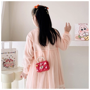 Detail of red silicone mini bag with pearl handle, diamond texture, and cute 3D charms