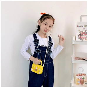 Detail of yellow jelly purse with pearl handle and cartoon charms on a young girl