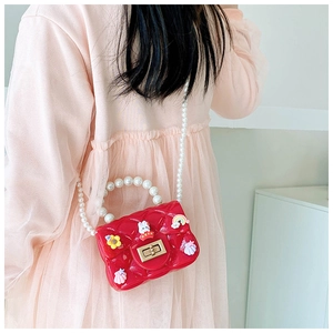 Detail of red silicone jelly bag with pearl handle and cartoon charms on young girl