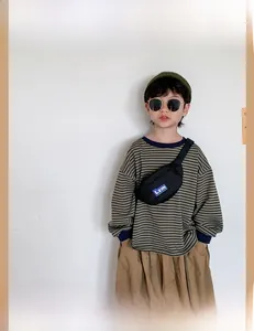 Close-up of child wearing black canvas chest bag with Lzm logo and adjustable strap