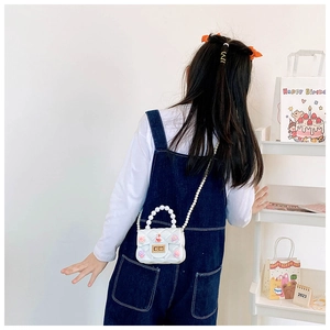 Vista posteriore di una bimba con borsa mini jelly bianca, manico di perle e decoro conchiglia
