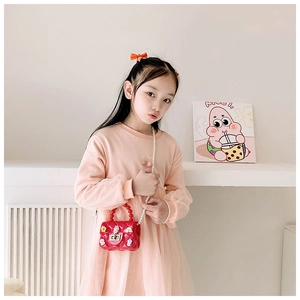 Close-up of red mini jelly bag with floral accents and pearl strap on a young girl